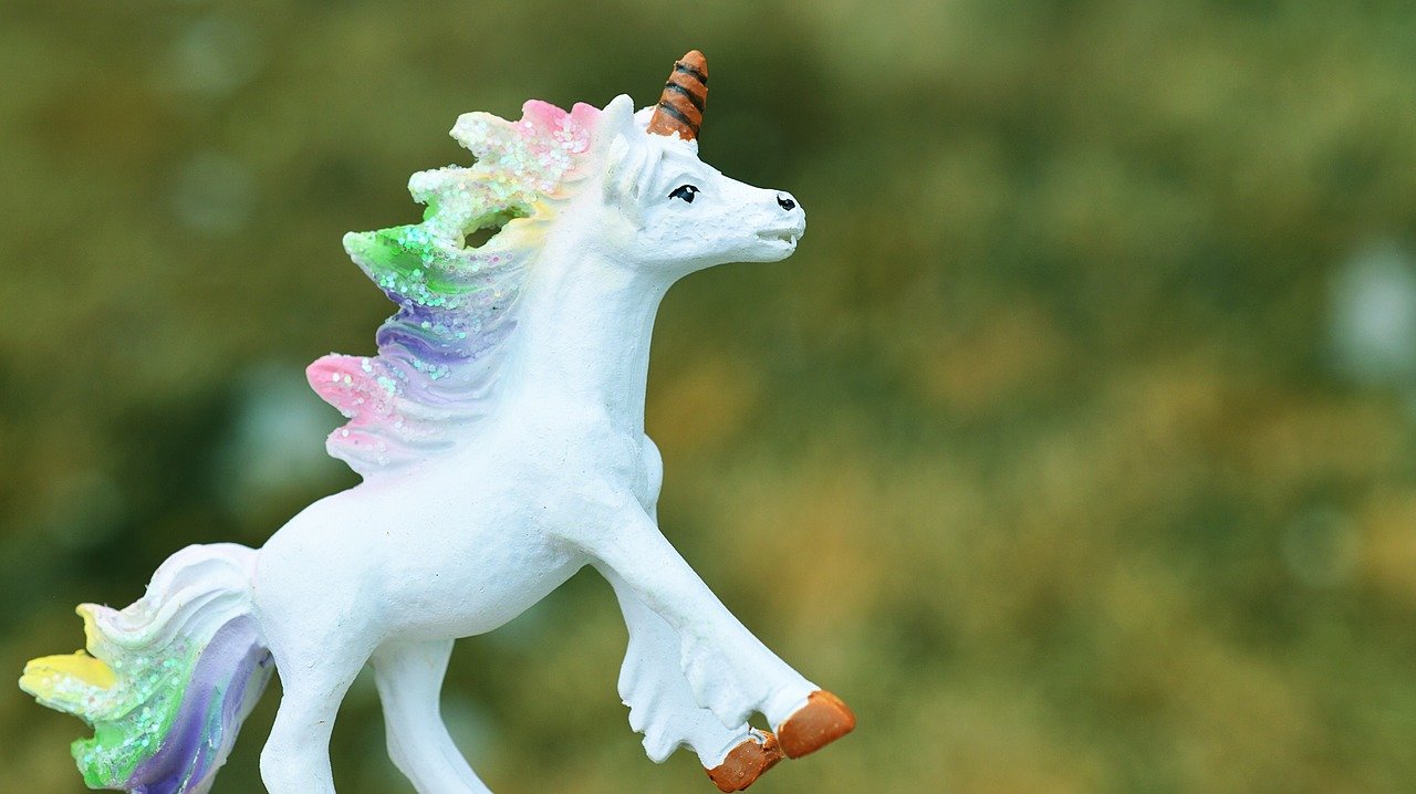 Une licorne jouet gambader dans un champ herbeux.